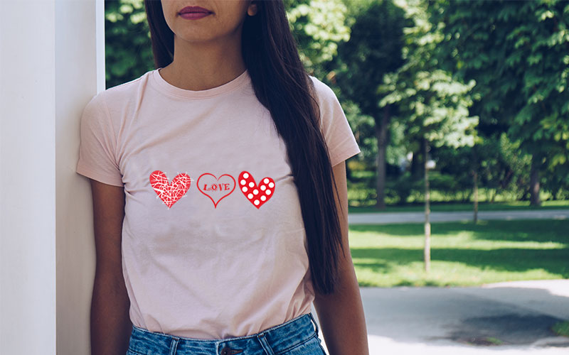 A preview of a woman wearing a  peach t-shirt with cute pink heart, love heart, and polka dot heart SVG printed on it