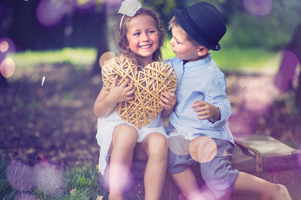 two kids and sitting holding a heart
