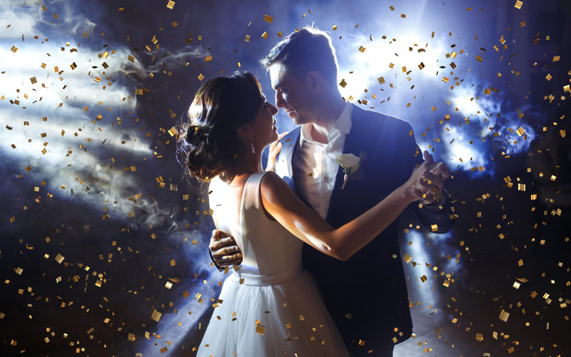 An image of a couple dancing under the falling gold confetti.